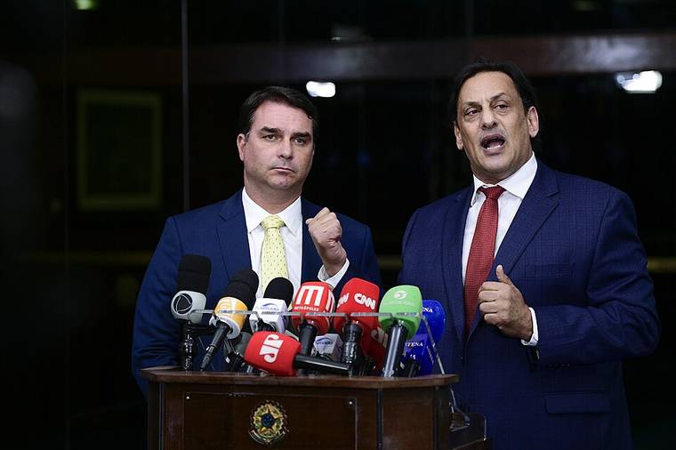 Flávio Bolsonaro ao lado do advogado Frederick Wassef diante de microfones